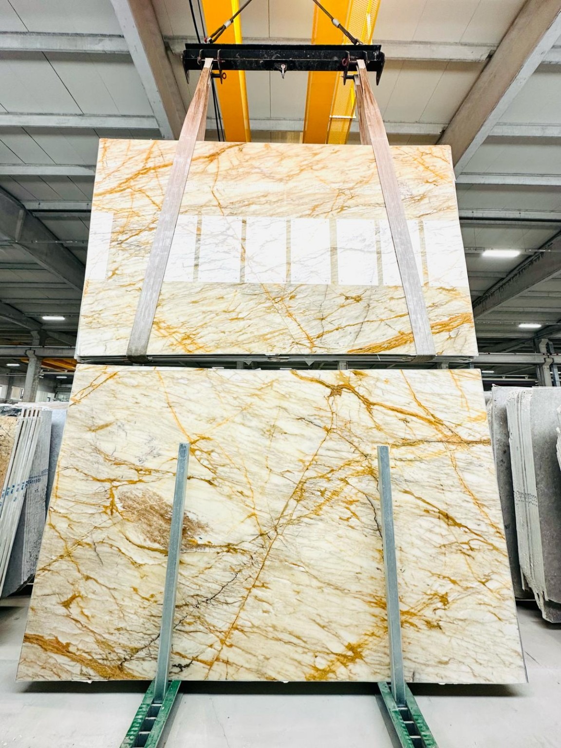 Golden-veined stone slab being handled at the warehouse